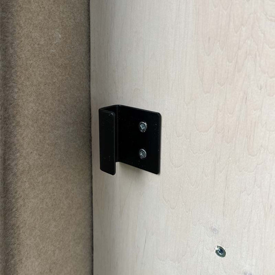 Schwarzer Befestigungswinkel an der Wand eines Möbels in einem ausgebauten Transporter befestigt