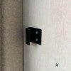 Black fixing bracket attached to the wall of a cabinet in a converted van