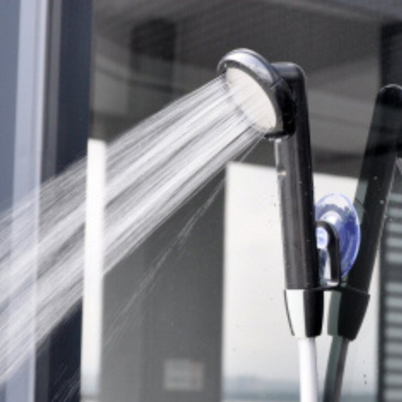 Autonome tragbare Dusche mit Akku, verwendet an der Rückseite eines ausgebauten Transporters für eine Toilette im Freien.