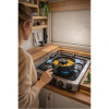 Woman in beige jumper using the TANDOOR nomad oven on a gas hob in a fitted van kitchen